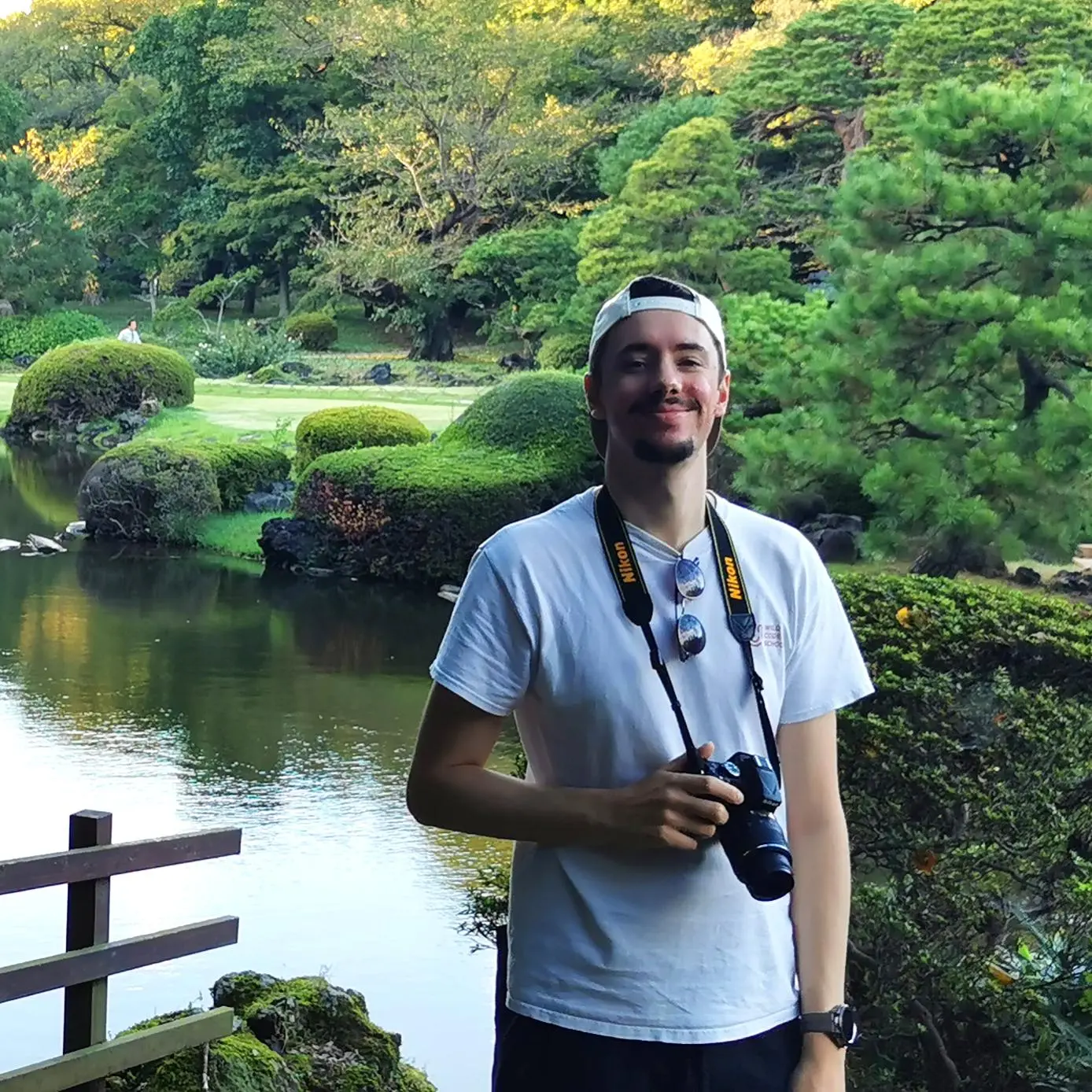 Un photo de Louis Lesage se tenant devant un étang dans un parc.